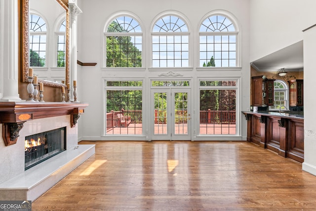 11569 Finley Rd, Johns Creek, GA 30024 - unfurnished living room with a towering ceiling, a high end fireplace, wood finished floors, healthy amount of natural light, and a sink