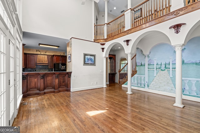 11569 Finley Rd, Johns Creek, GA 30024 - unfurnished living room featuring a high ceiling, decorative columns, light wood-type flooring, baseboards, and ceiling fan