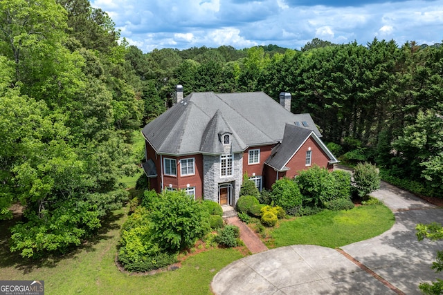 11569 Finley Rd, Johns Creek, GA 30024 - view of front facade with stone siding, a chimney, a forest view, and a front lawn
