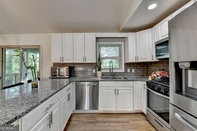 1358 Millstream Trl, Lawrenceville, GA 30044 - kitchen featuring stainless steel appliances, a sink, light stone counters, light wood-style flooring, and white cabinets