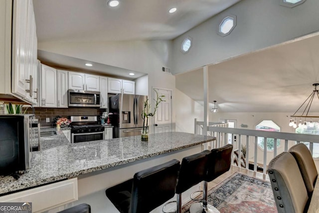 1358 Millstream Trl, Lawrenceville, GA 30044 - kitchen with appliances with stainless steel finishes, a peninsula, light stone counters, a kitchen breakfast bar, and white cabinets