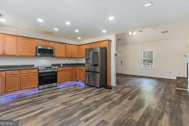 220 Windpher Rdg, Hampton, GA 30228 - kitchen featuring appliances with stainless steel finishes, dark wood-style flooring, brown cabinetry, baseboards, and a textured ceiling