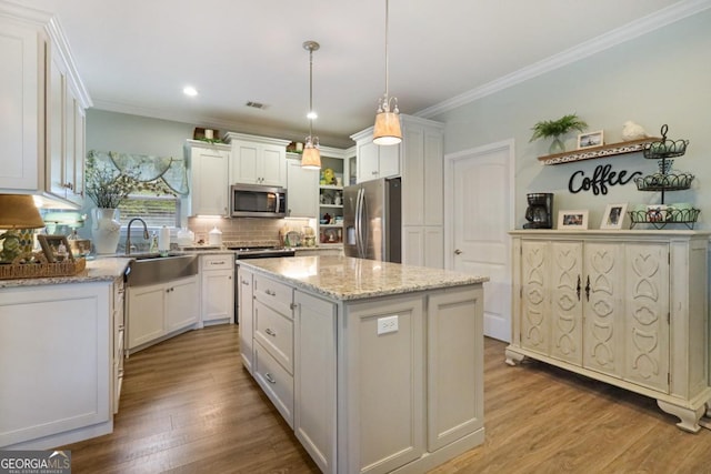 156 Hannah Dr, Jesup, GA 31546 - kitchen with stainless steel appliances, a kitchen island, wood finished floors, decorative backsplash, and ornamental molding