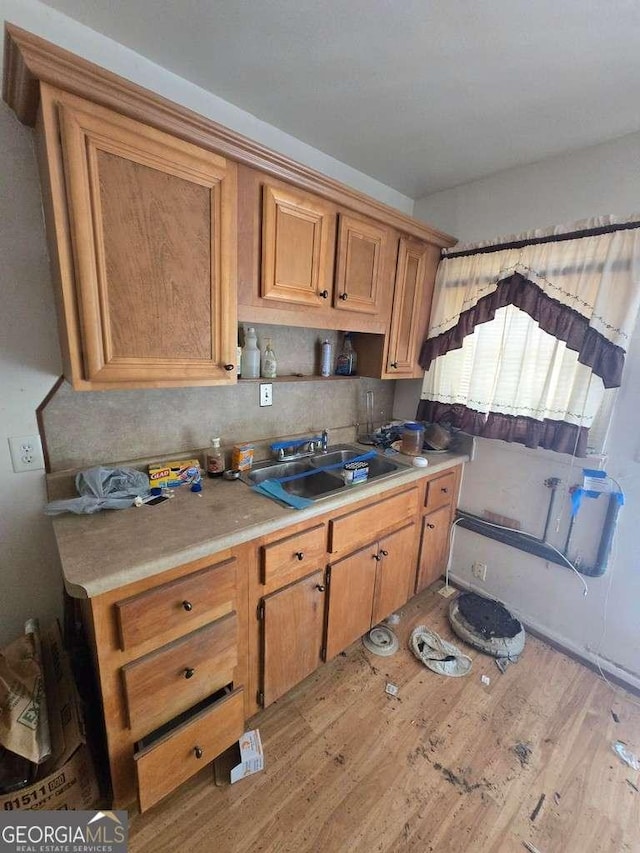 25 Candler Rd SE, Atlanta, GA 30317 - kitchen featuring a sink, light countertops, light wood-style flooring, brown cabinetry, and tasteful backsplash