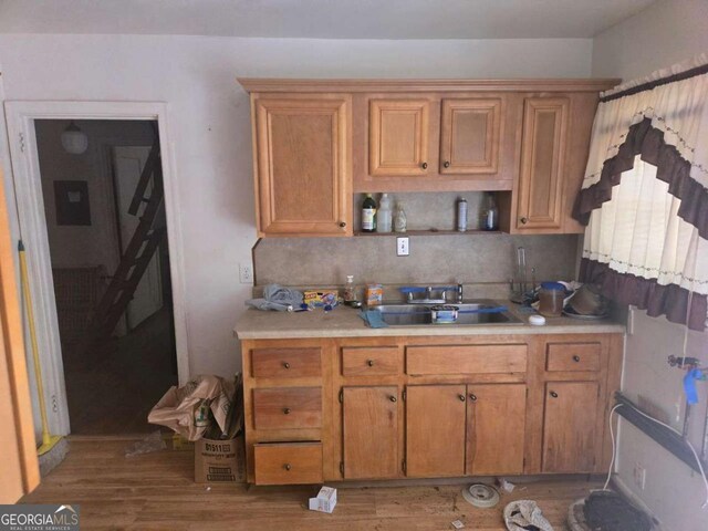 25 Candler Rd SE, Atlanta, GA 30317 - kitchen with a sink, light countertops, light wood-style flooring, brown cabinetry, and decorative backsplash