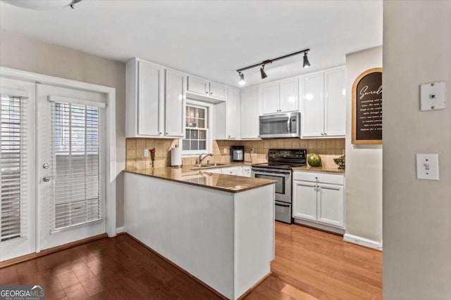 1101 Collier Rd NW Unit K2, Atlanta, GA 30318 - kitchen featuring appliances with stainless steel finishes, white cabinetry, backsplash, wood finished floors, and rail lighting