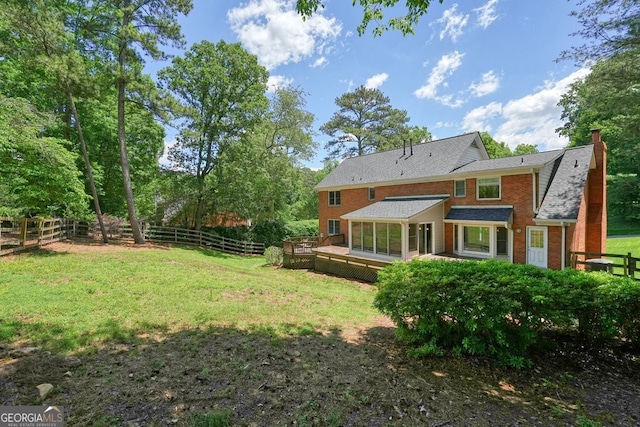 10310 Amberside Ct, Roswell, GA 30076 - back of property featuring a wooden deck, a sunroom, a chimney, a shingled roof, and brick siding