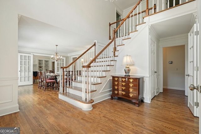10310 Amberside Ct, Roswell, GA 30076 - stairs featuring a chandelier, wood finished floors, ornamental molding, a decorative wall, and french doors
