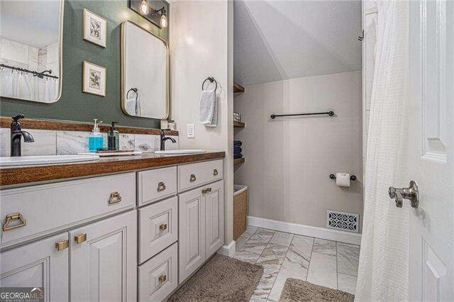 bathroom with marble finish floors, double vanity, lofted ceiling, a shower with curtain, and baseboards