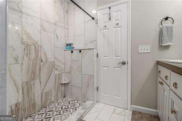 bathroom featuring tiled shower, vanity, and baseboards