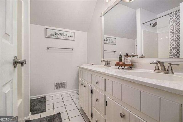 bathroom featuring vaulted ceiling, tile patterned flooring, double vanity, and a shower