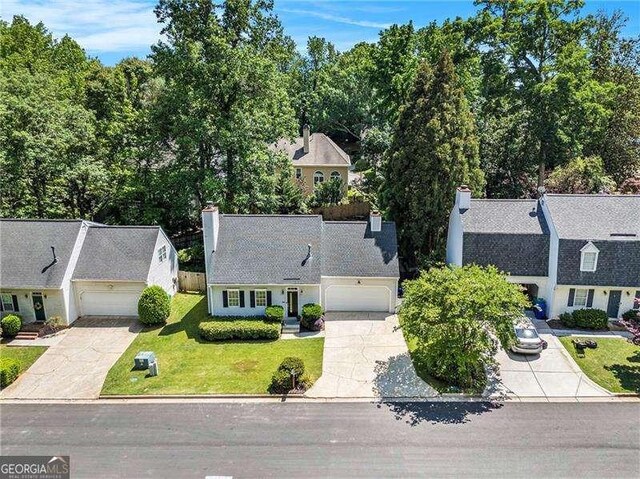 view of front of property featuring concrete driveway, a chimney, a garage, and a front yard