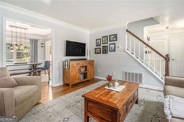 living area with stairway, crown molding, baseboards, and wood finished floors