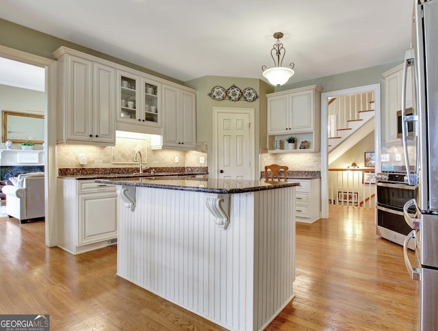 150 Bay Dr, Newnan, GA 30263 - kitchen featuring a breakfast bar area, tasteful backsplash, light wood-style floors, dark stone countertops, and decorative light fixtures