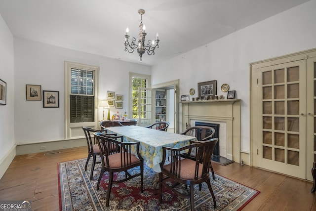 171 N Jefferson Ave, Talbotton, GA 31827 - dining room featuring a chandelier, a fireplace with raised hearth, hardwood / wood-style floors, and baseboards