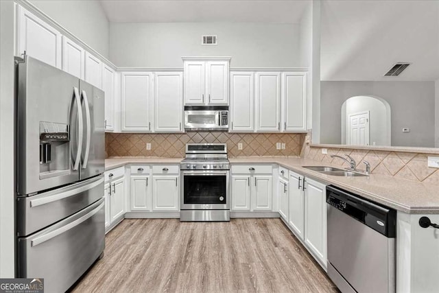 613 Wiley Ct, Canton, GA 30115 - kitchen featuring appliances with stainless steel finishes, light countertops, white cabinets, light wood-type flooring, and backsplash