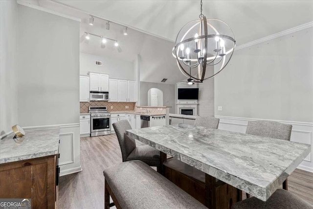 613 Wiley Ct, Canton, GA 30115 - dining space with light wood-style floors, a chandelier, a fireplace, a wainscoted wall, and ornamental molding