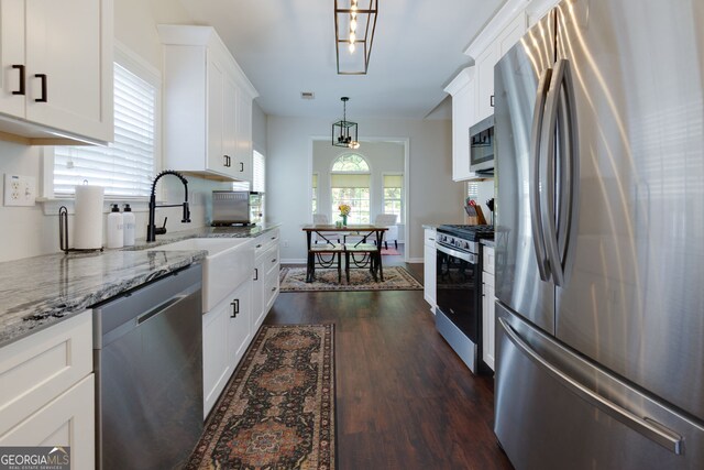 kitchen featuring stainless steel appliances, dark wood finished floors, light stone countertops, white cabinets, and decorative light fixtures