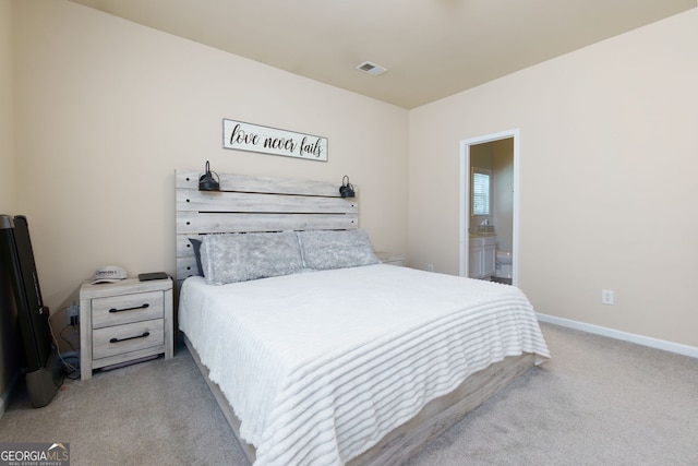 bedroom featuring light carpet, ensuite bath, and baseboards
