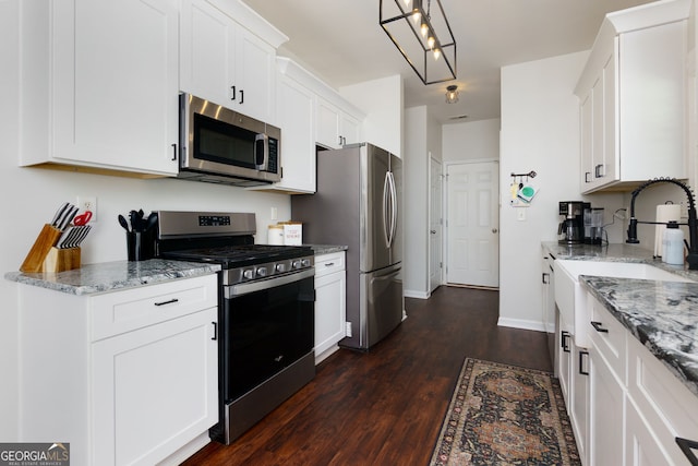 kitchen with appliances with stainless steel finishes, dark wood-style flooring, light stone counters, white cabinetry, and baseboards
