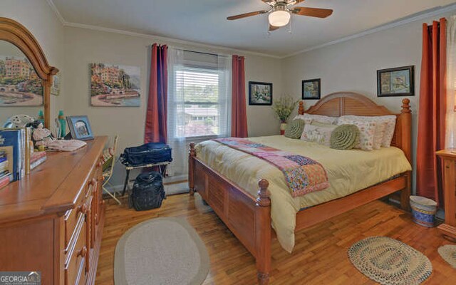 bedroom featuring light wood-style floors, crown molding, and ceiling fan