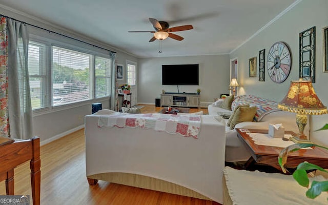 living room featuring plenty of natural light, wood finished floors, ceiling fan, ornamental molding, and baseboards