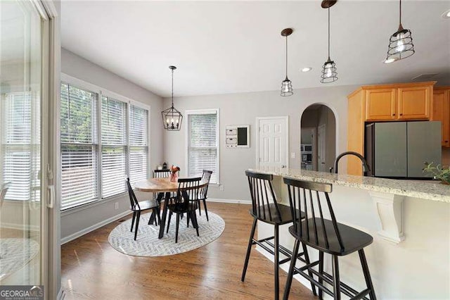 101 Misty Valley Dr, Canton, GA 30114 - kitchen featuring freestanding refrigerator, baseboards, arched walkways, a kitchen breakfast bar, and wood finished floors