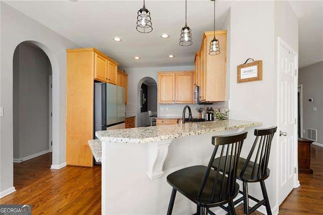 101 Misty Valley Dr, Canton, GA 30114 - kitchen with arched walkways, a peninsula, light brown cabinets, dark wood finished floors, and appliances with stainless steel finishes