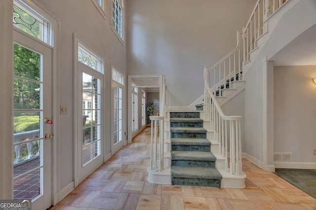 foyer with a high ceiling, stairs, baseboards, and french doors