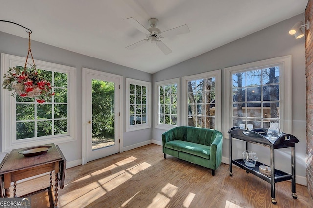 sunroom / solarium with plenty of natural light, vaulted ceiling, baseboards, wood finished floors, and a deck
