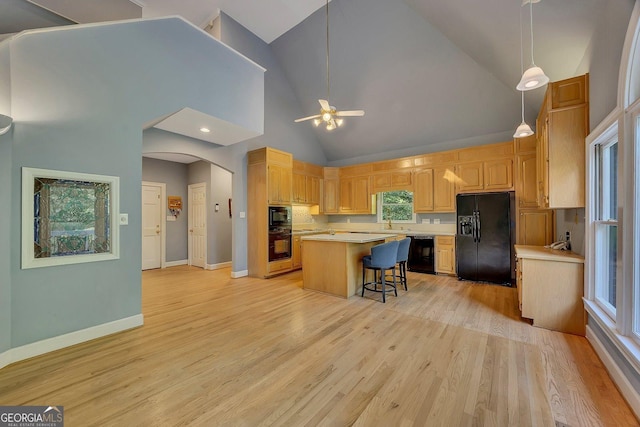 kitchen with black appliances, light countertops, light wood finished floors, baseboards, and a kitchen island
