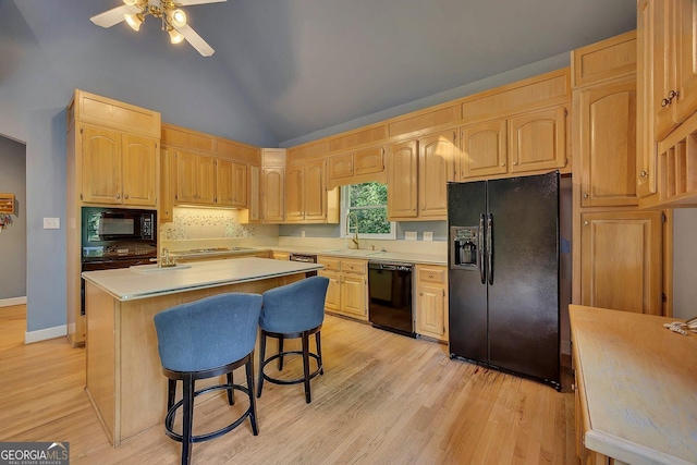 kitchen with black appliances, light brown cabinets, a sink, and lofted ceiling
