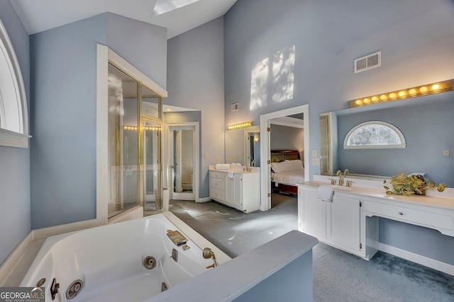 ensuite bathroom featuring high vaulted ceiling, a jetted tub, vanity, and baseboards