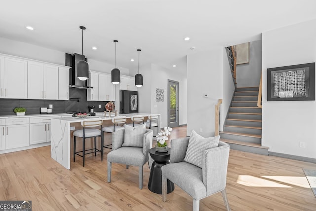3378 Bachelor St, Atlanta, GA 30344 - kitchen featuring wall chimney exhaust hood, refrigerator, light countertops, tasteful backsplash, and an island with sink