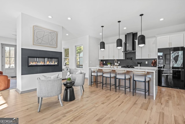 3378 Bachelor St, Atlanta, GA 30344 - kitchen with freestanding refrigerator, wall chimney range hood, light wood-style floors, white cabinets, and recessed lighting