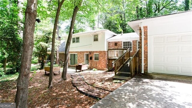 2620 Clairmont Rd, Atlanta, GA 30329 - rear view of property with brick siding, driveway, a garage, and a wooden deck
