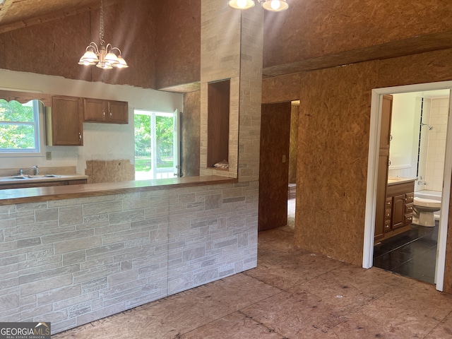 kitchen featuring a sink, healthy amount of natural light, high vaulted ceiling, a chandelier, and light countertops