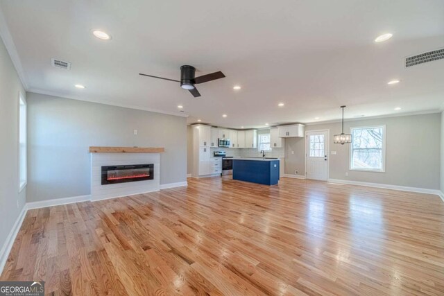 2741 Pierce Rd, Gainesville, GA 30507 - unfurnished living room featuring crown molding, a glass covered fireplace, baseboards, recessed lighting, and light wood-type flooring