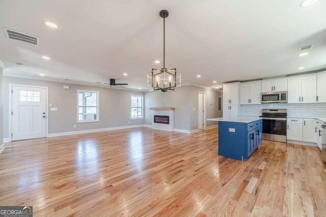 2741 Pierce Rd, Gainesville, GA 30507 - kitchen with appliances with stainless steel finishes, light countertops, white cabinetry, a kitchen island, and light wood-style floors