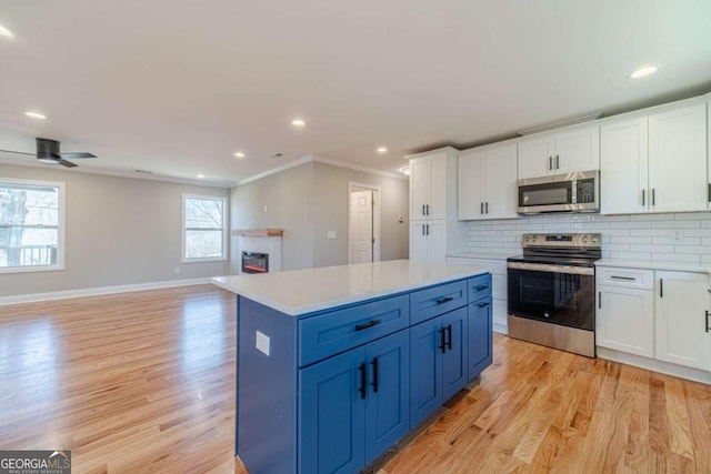 2741 Pierce Rd, Gainesville, GA 30507 - kitchen with stainless steel appliances, ornamental molding, light wood-style floors, a glass covered fireplace, and white cabinets