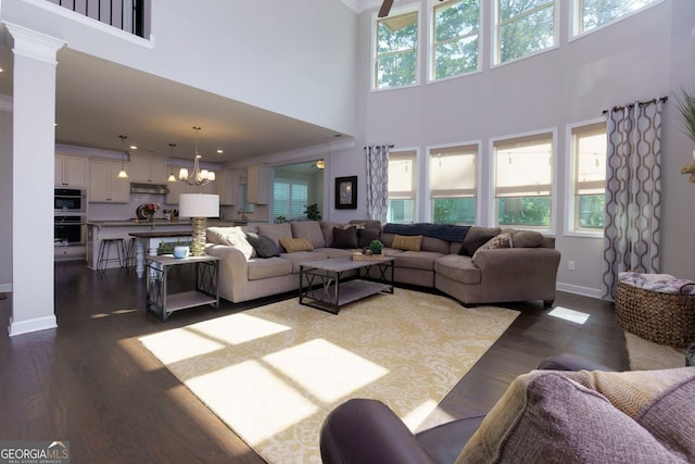 living area featuring a high ceiling, dark wood-style flooring, a chandelier, and baseboards
