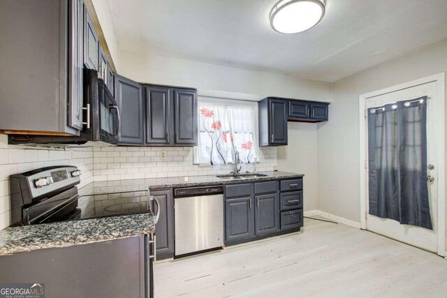 2564 Riggs Dr, East Point, GA 30344 - kitchen featuring stainless steel appliances, light wood-style floors, decorative backsplash, and dark stone counters