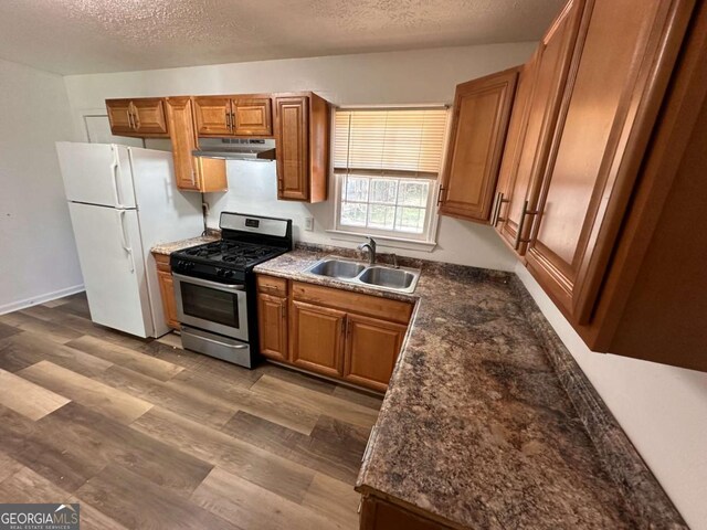 2872 Harris St, Atlanta, GA 30344 - kitchen featuring stainless steel range with gas stovetop, a sink, under cabinet range hood, freestanding refrigerator, and brown cabinetry