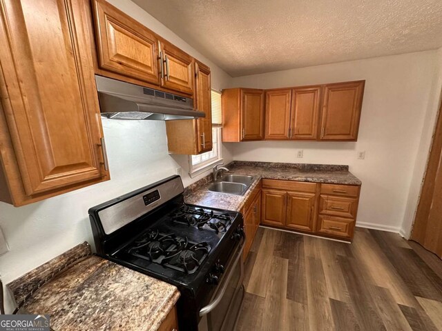 2872 Harris St, Atlanta, GA 30344 - kitchen featuring stainless steel range with gas stovetop, under cabinet range hood, a sink, dark wood-style flooring, and brown cabinetry