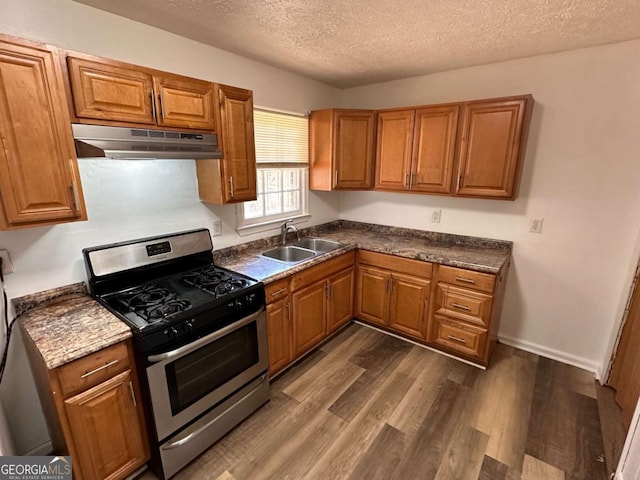 2872 Harris St, Atlanta, GA 30344 - kitchen featuring under cabinet range hood, stainless steel gas stove, a textured ceiling, a sink, and brown cabinetry