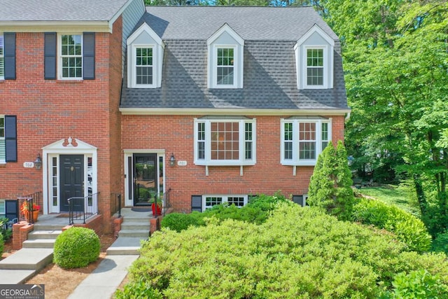 view of front of house with roof with shingles and brick siding