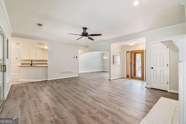 703 Kirkwood Cir, Woodstock, GA 30189 - unfurnished living room with ceiling fan, ornamental molding, light wood finished floors, arched walkways, and baseboards