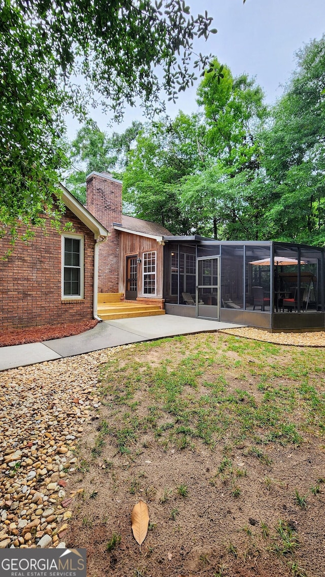 213 Falcon Crst, Warner Robins, GA 31088 - rear view of house featuring a chimney, a sunroom, brick siding, and a patio