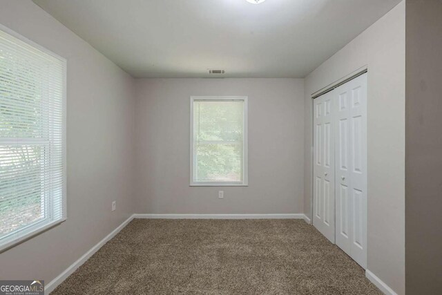 1808 Arkose Dr SE, Atlanta, GA 30316 - unfurnished bedroom with multiple windows, carpet floors, baseboards, and a closet