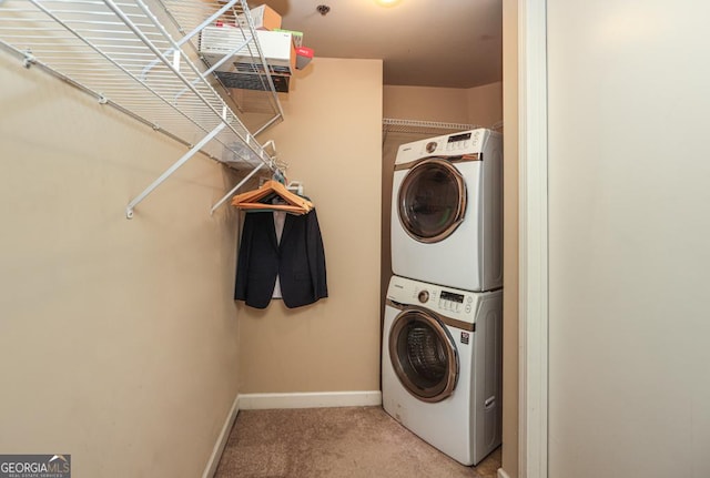 clothes washing area featuring stacked washer / dryer, light colored carpet, and baseboards